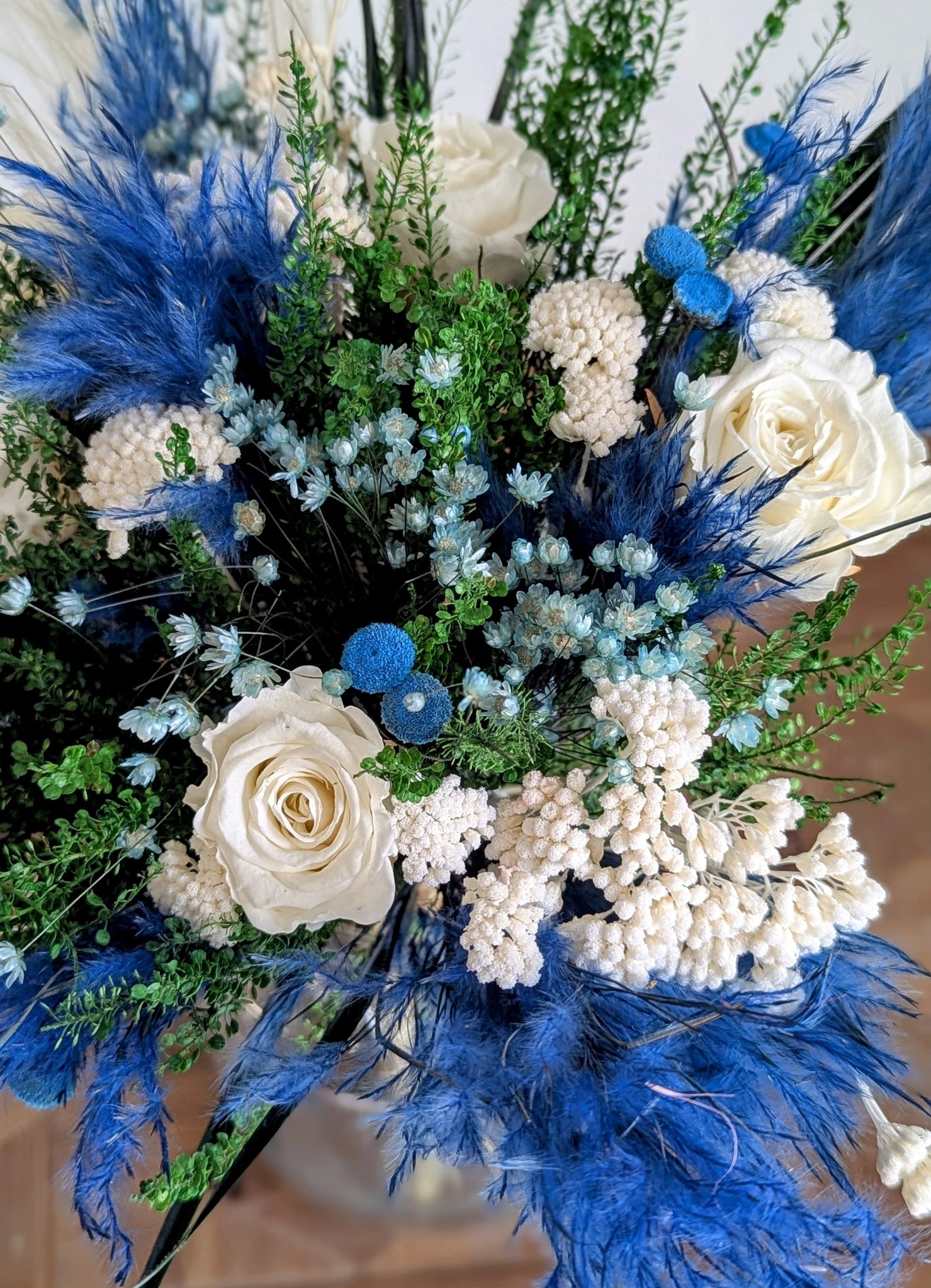 Bouquet élégant de fleurs stabilisées à dominante bleue et blanche dans un vase déco