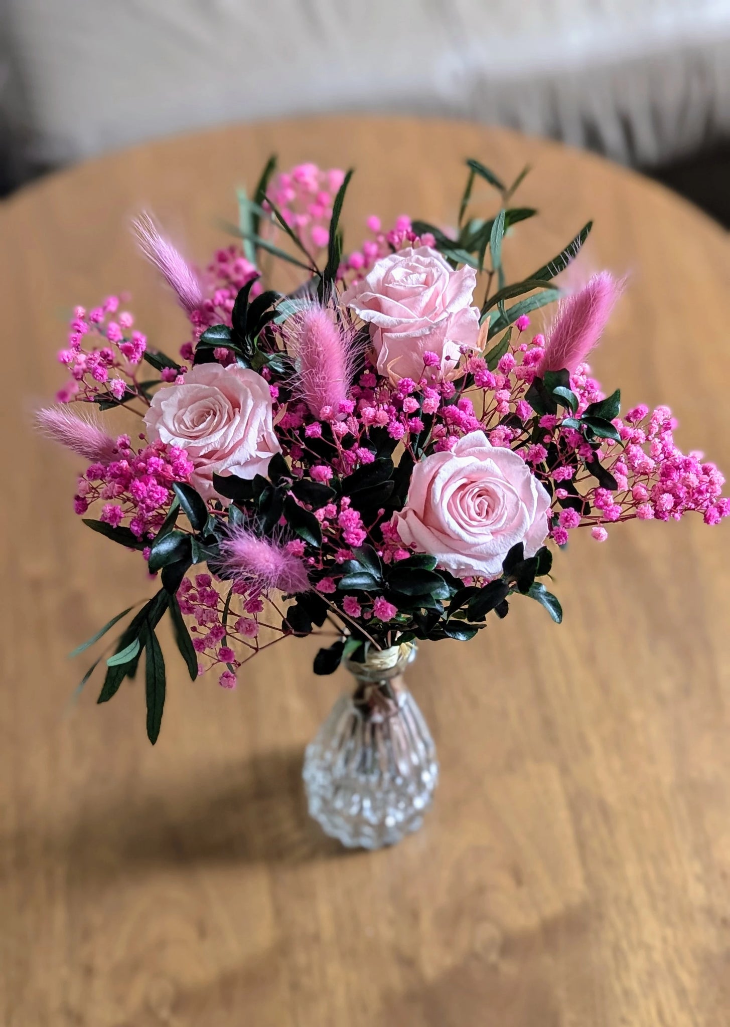 Bouquet MYA de fleurs stabilisées roses dans un vase en verre travaillé.