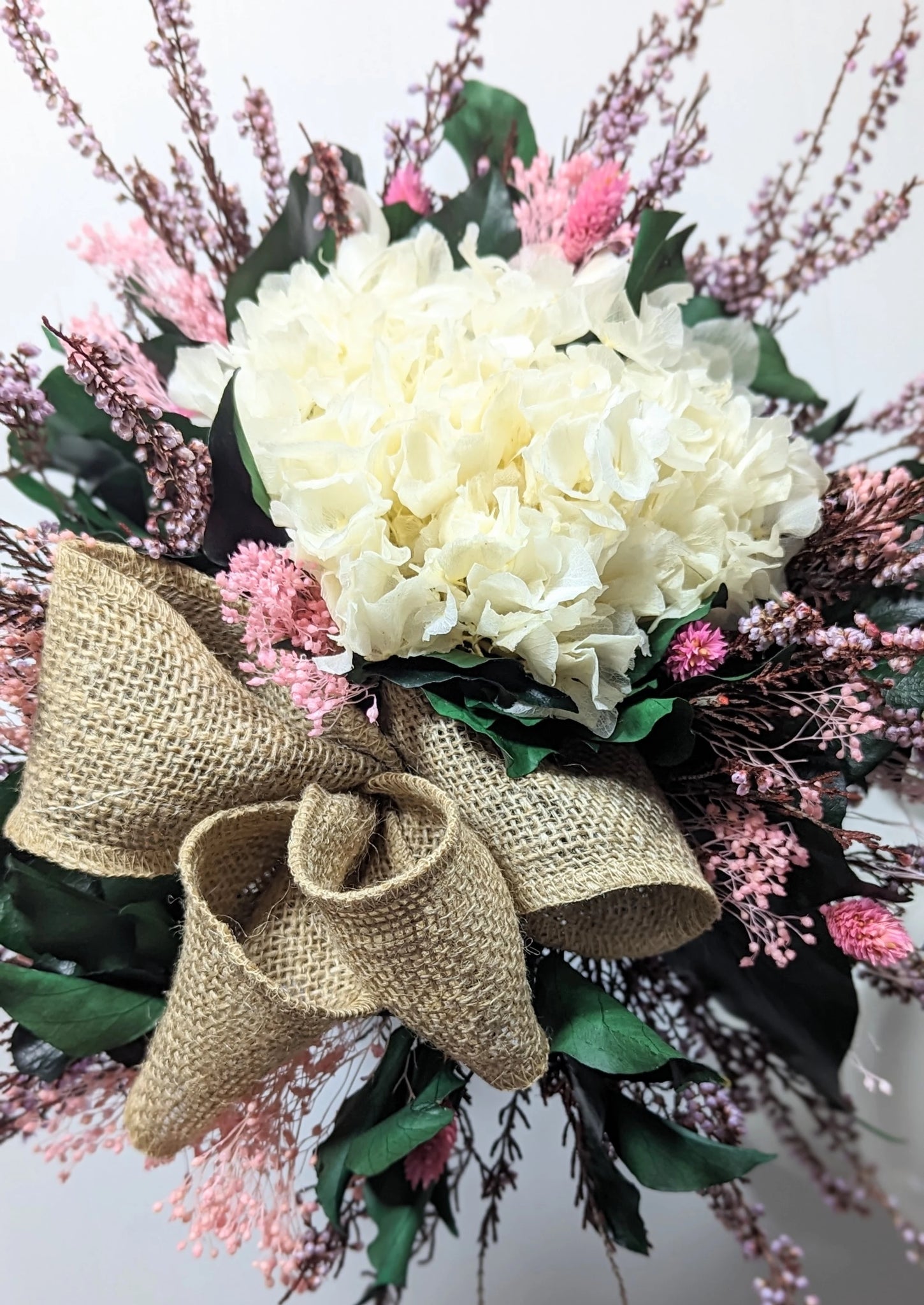 Un bouquet romantique aux fleurs stabilisées, alliant blanc éclatant, rose pastel et un élégant nœud en toile de jute. Une création durable et raffinée pour sublimer votre intérieur ou offrir un cadeau unique, rempli de poésie.