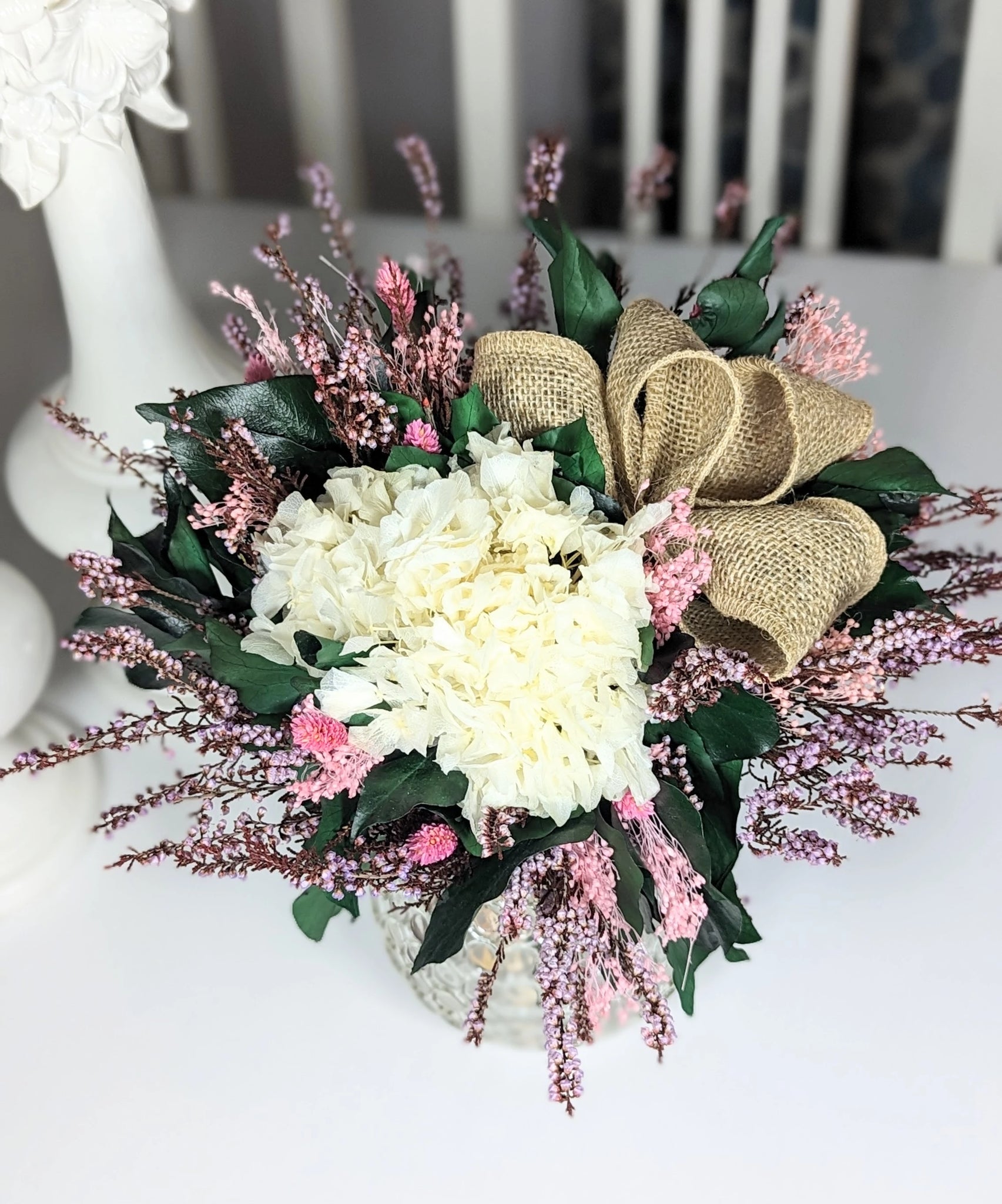 Ce bouquet en fleurs stabilisées marie douceur et élégance avec ses teintes blanches et roses, rehaussées par un nœud en jute naturel. Une décoration intemporelle pour apporter une touche chaleureuse et délicate à votre vote.