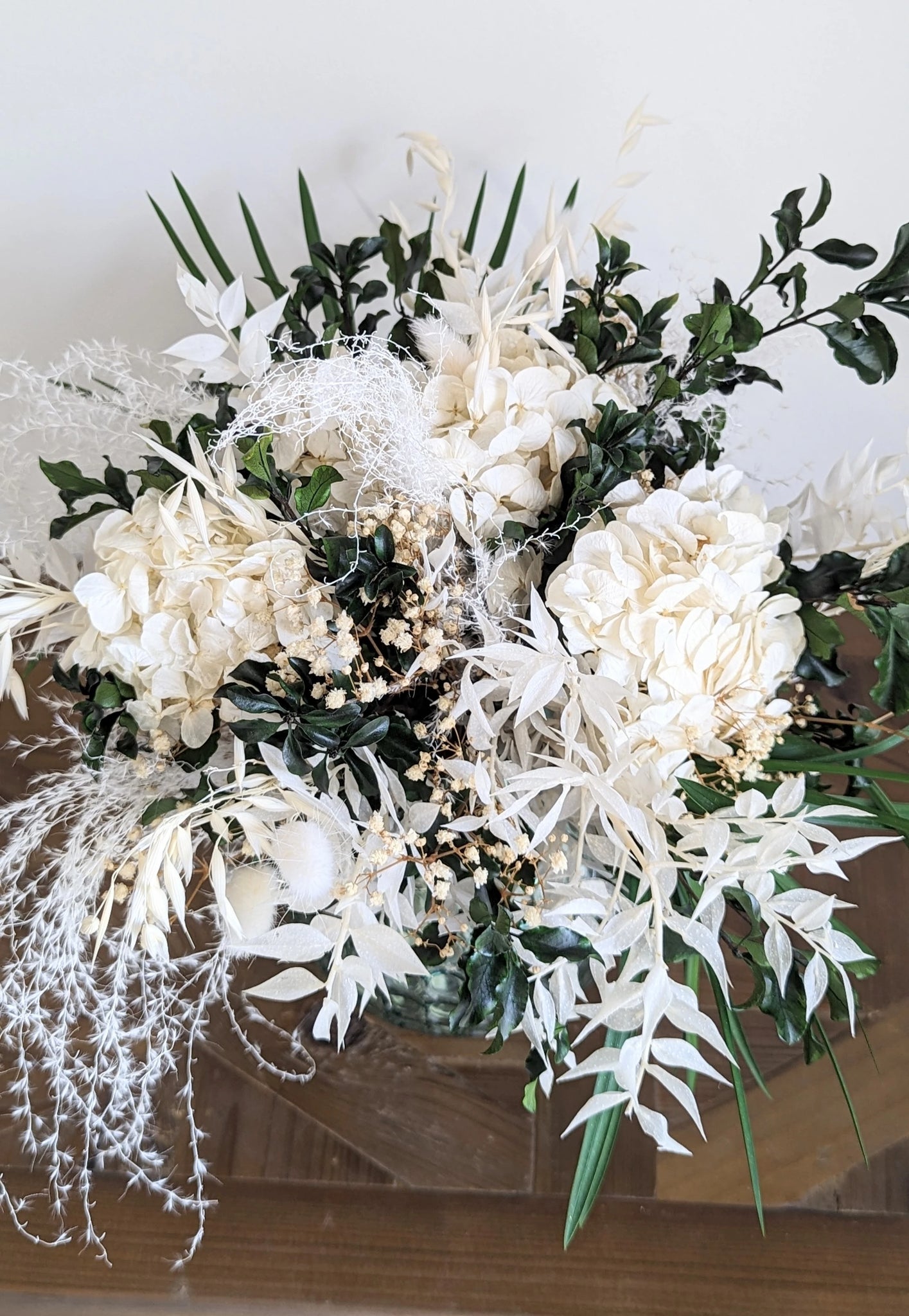 L'art floral éternel : Blanc éclatant et verdure vibrante s'unissent dans ce bouquet qui allie grâce et durabilité, pour embellir votre espace avec poésie. Bryanna