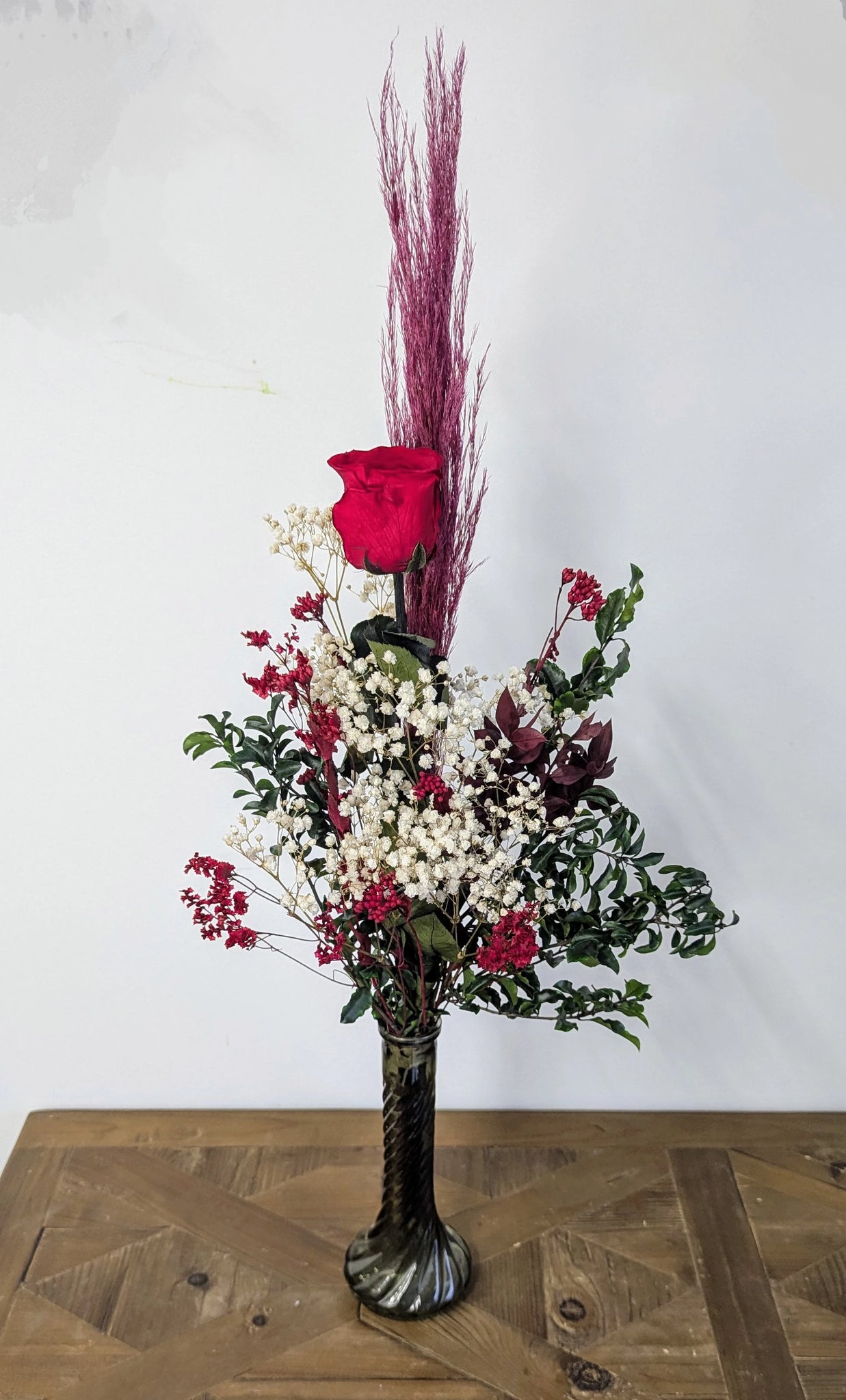 Bouquet en hauteur avec rose rouge et fleurs stabilisées élégantes.