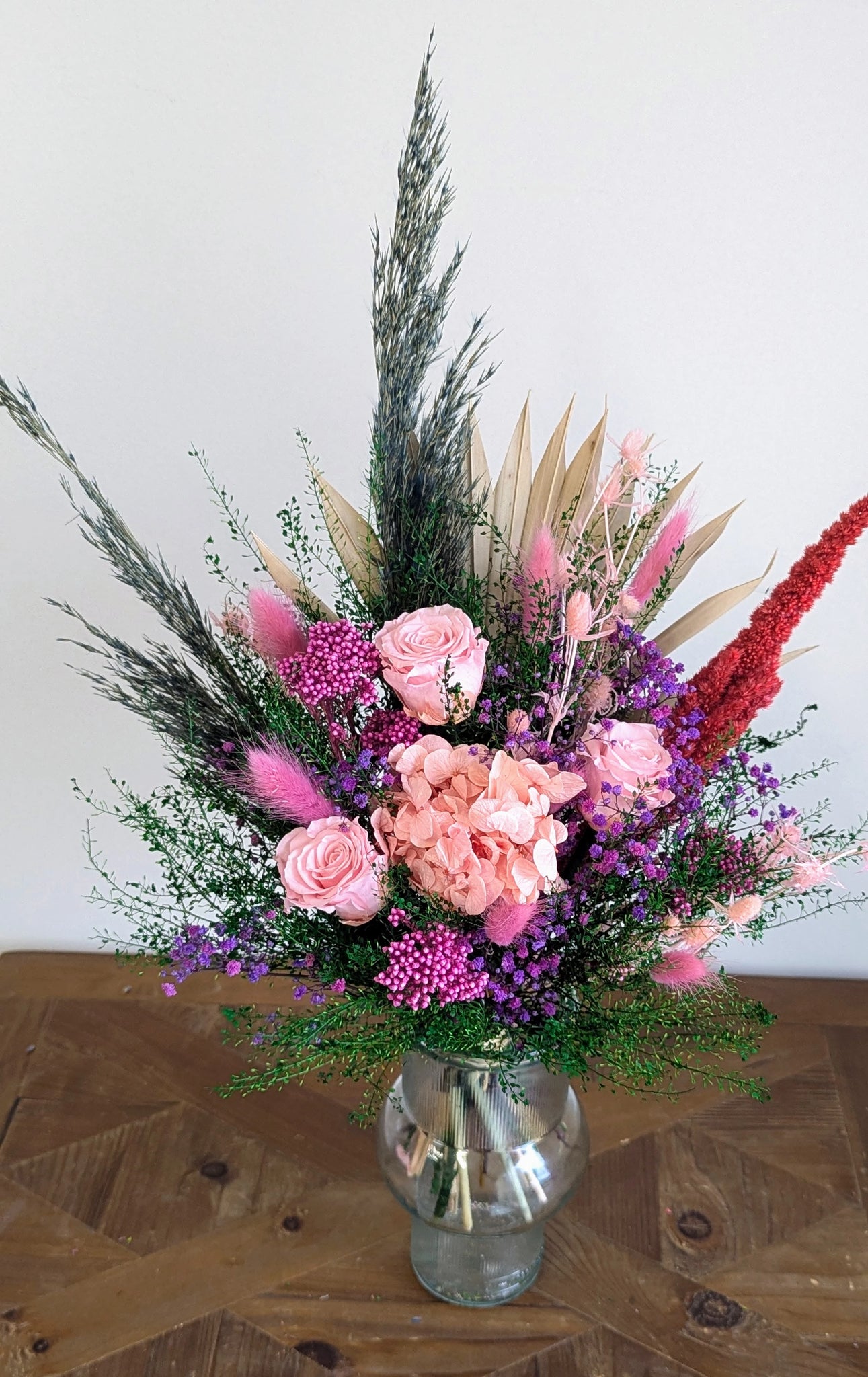 Bouquet ONESSA en fleurs stabilisées roses, violettes et rouges, avec feuillage vert.