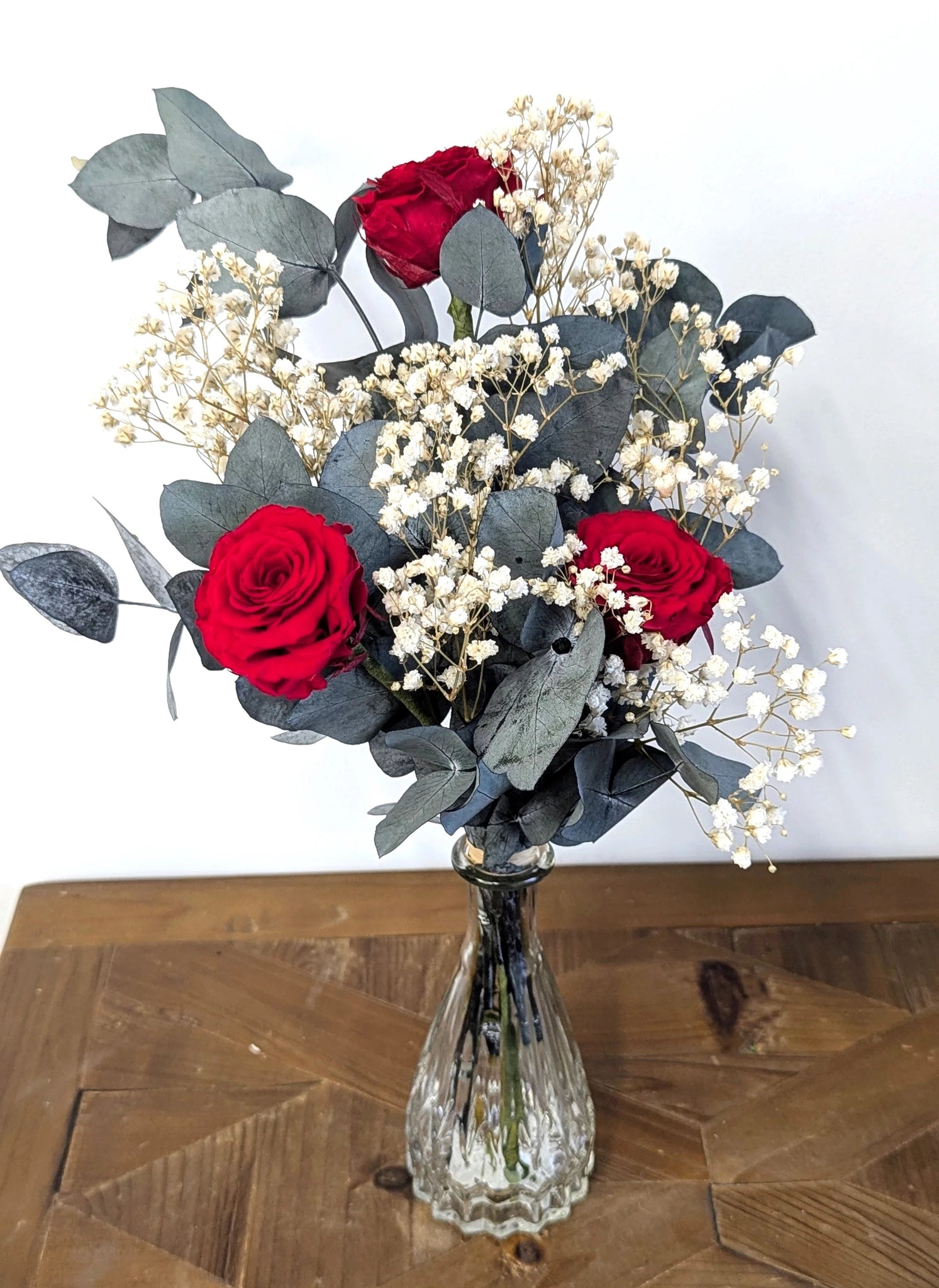 Composition artisanale de roses rouges et gypsophile en fleurs stabilisées.