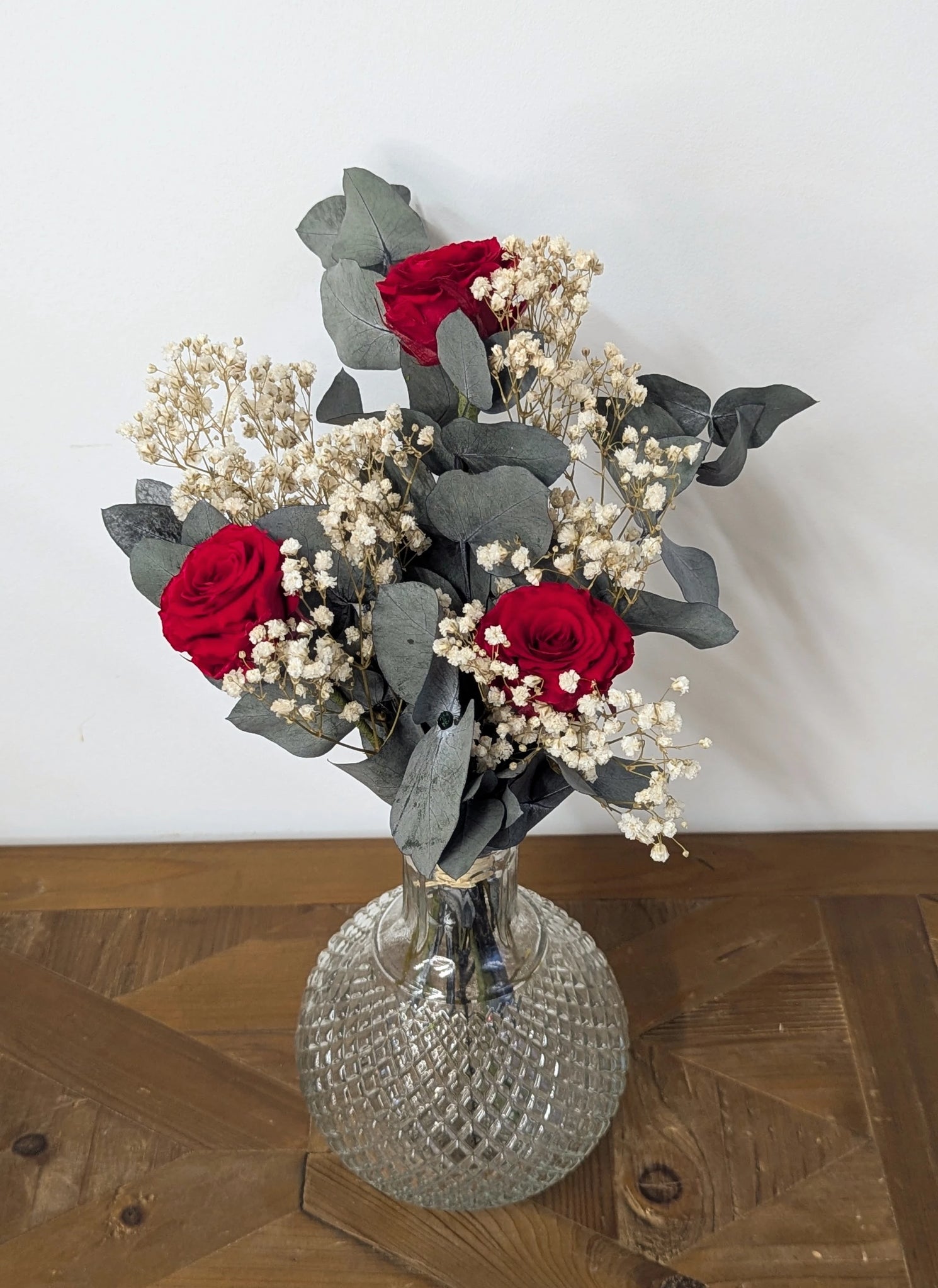 Composition artisanale de roses rouges et gypsophile en fleurs stabilisées.