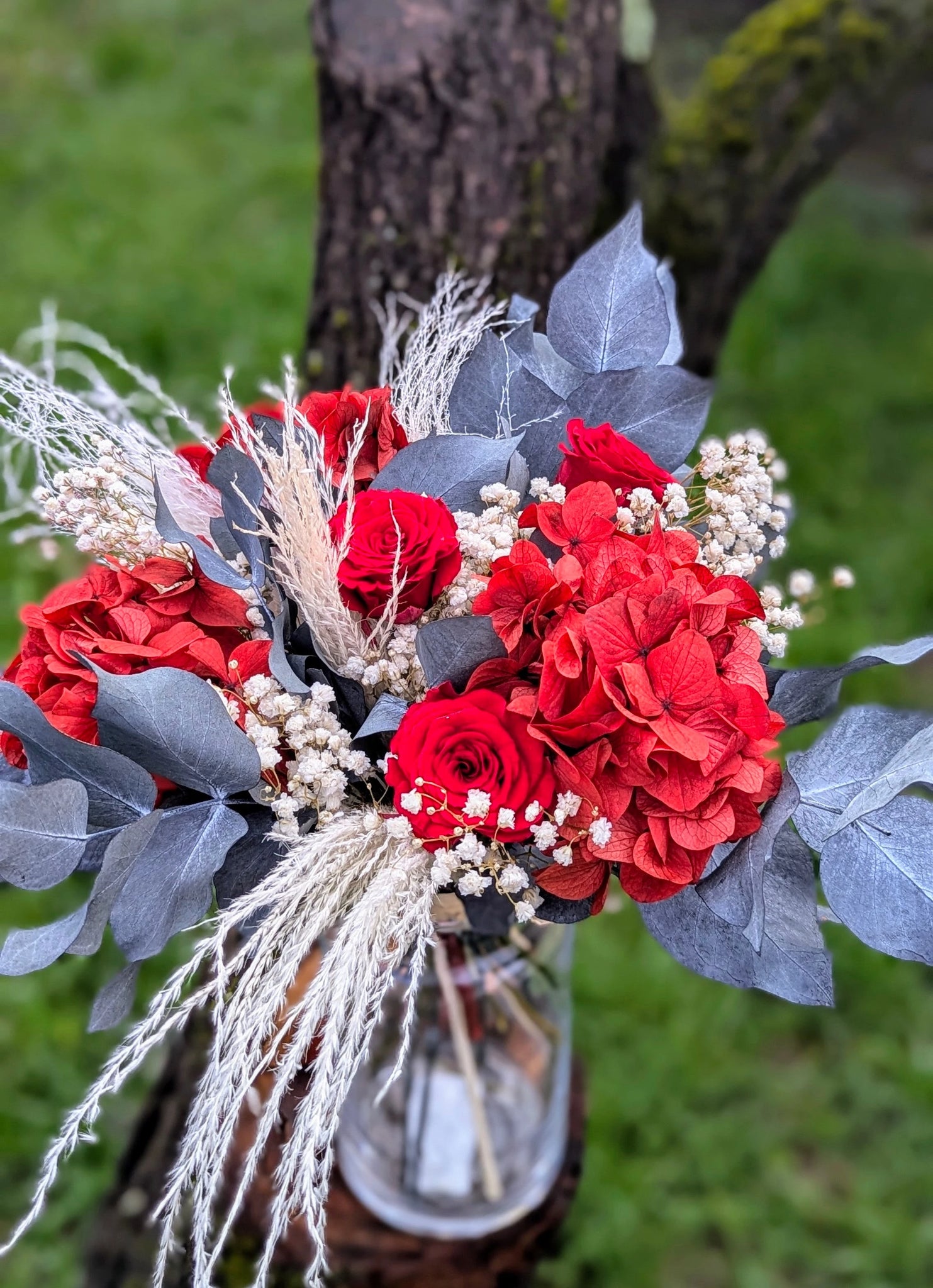 Un bouquet flamboyant où l’hydrangea rouge et les roses stabilisées se mêlent au gypsophile et au feuillage gris pour une composition audacieuse et élégante. 🌹 Une création qui capte le regard et traverse le temps.