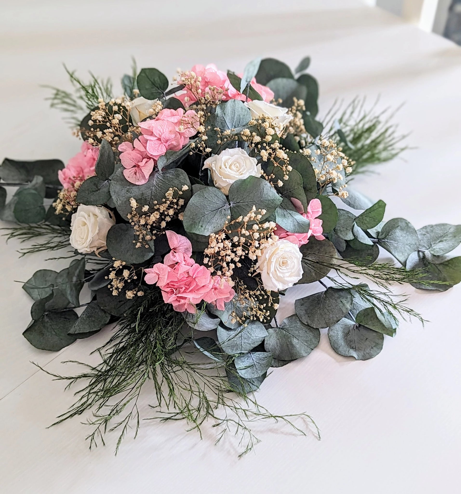 Centre de table mariage élégant en fleurs stabilisées, eucalyptus, hortensias roses et roses blanches pour une décoration romantique et durable.