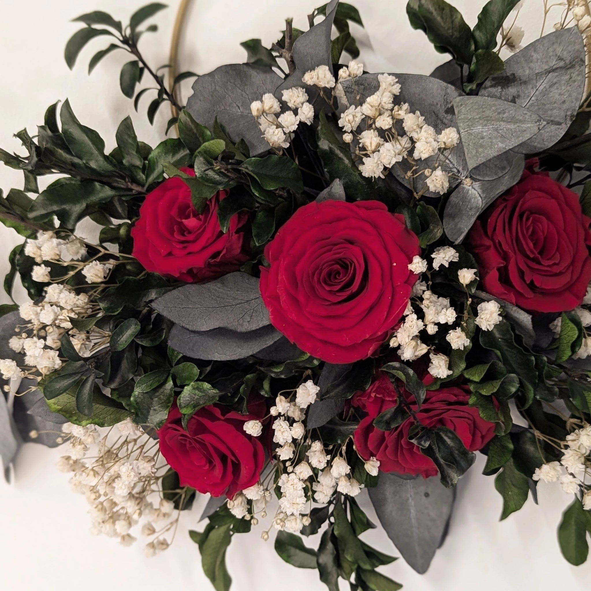 Couronne murale chic : fleurs stabilisées rouges, gypsophile et feuillage.