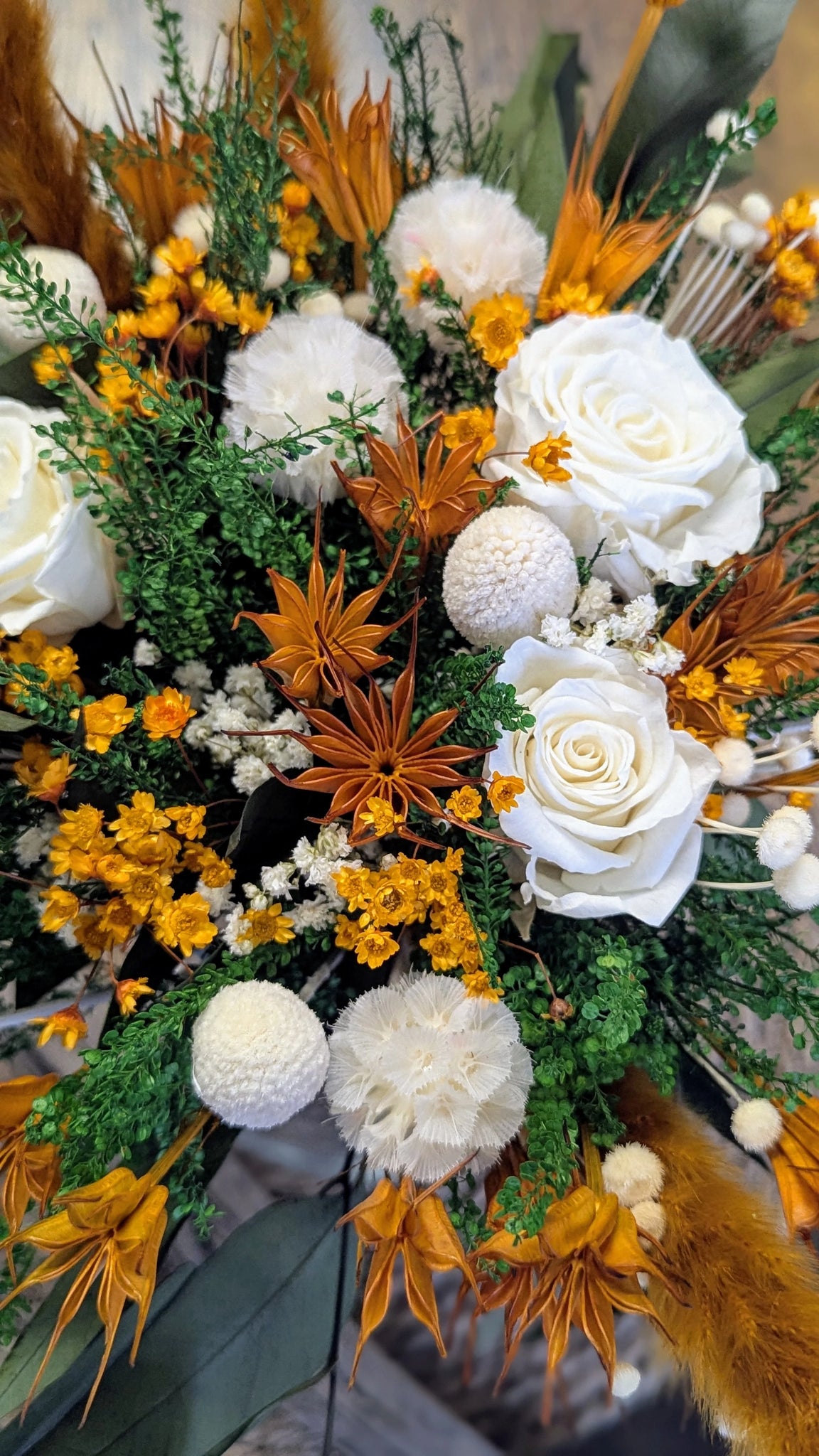 Vue rapprochée du bouquet ORIETA avec fleurs stabilisées aux tons orange et blanc.