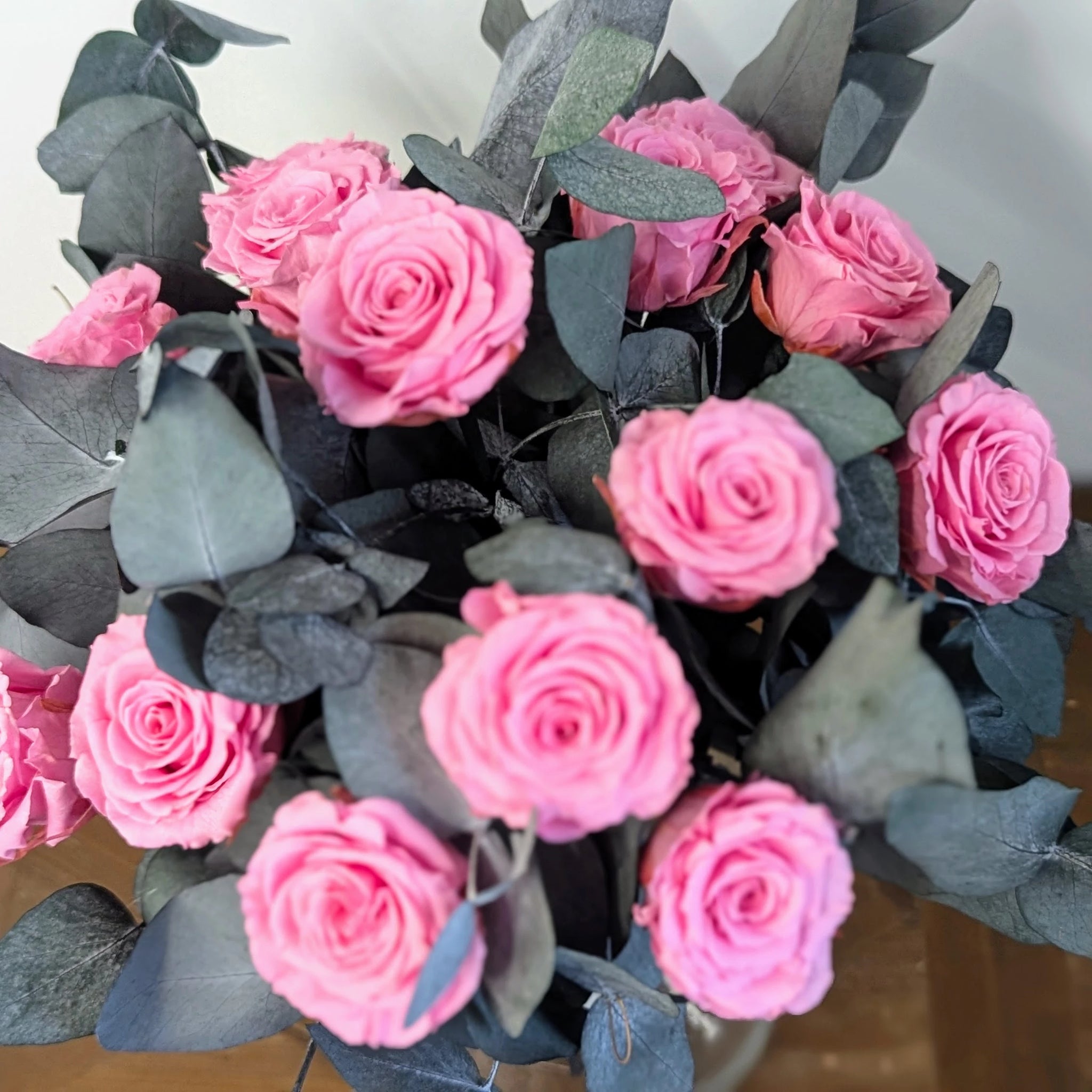 Brassée de roses stabilisées rose vif avec feuillage naturel