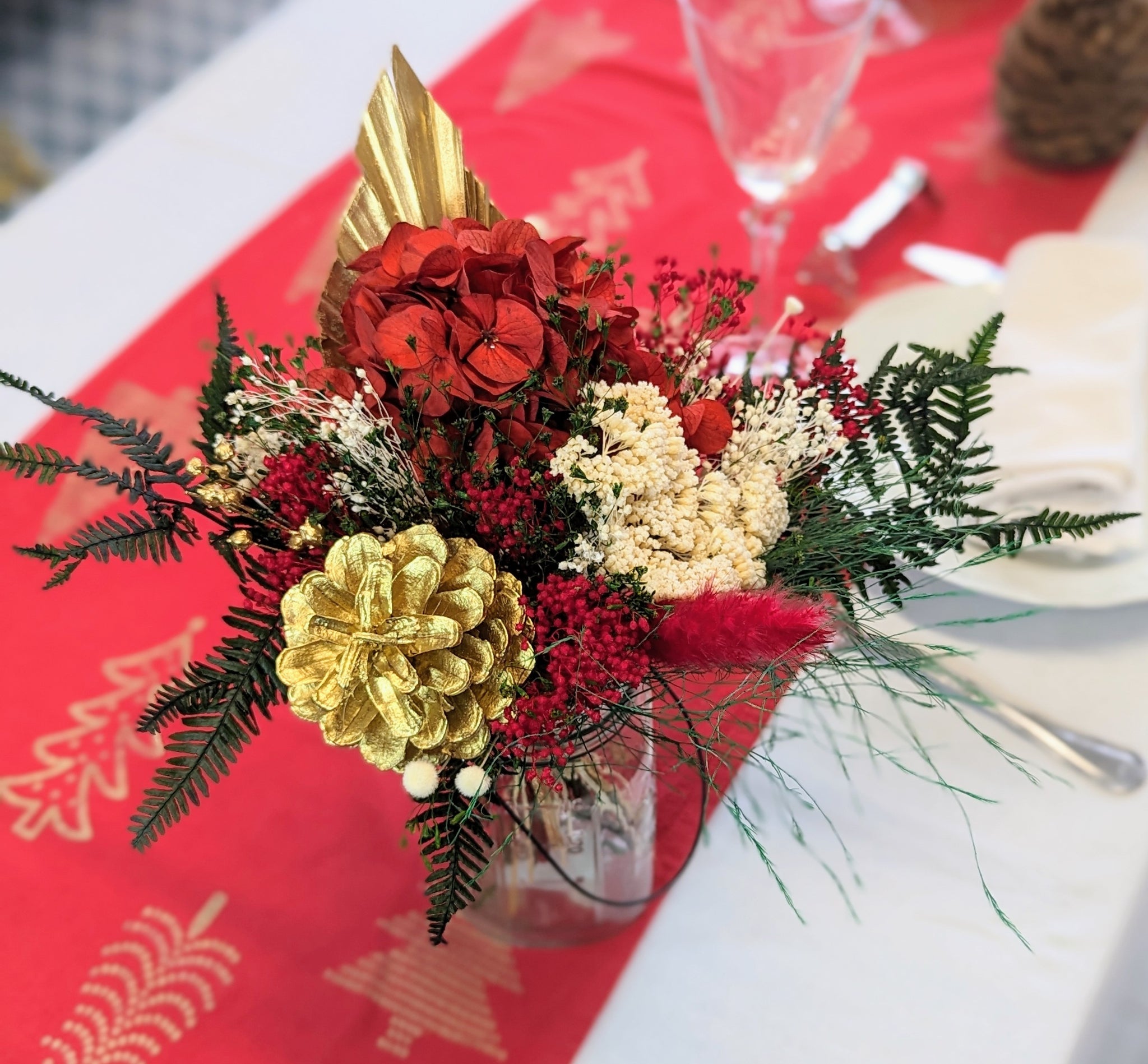 bouquet fleurs rouges, plume rouge, fleurs beiges sur chemin de table rouge